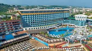 Antalya Havalimanı'ndan Okurcalar bölgesine VIP ulaşım sağlayan lüks Mercedes Vito araç, arkaplanda Granada Luxury Okurcalar'ın devasa iskelesi ve Karaburun koyu manzarası.